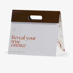 Sac cadeau Olfazeta by Chogan blanc à bande brune, inscription « Reveal your true essence » et flanc marbré